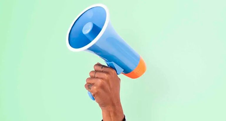 Pessoa segurando um megafone azul com fundo verde claro, simbolizando comunicação, divulgação ou anúncio eficaz em campanhas de marketing ou eventos.