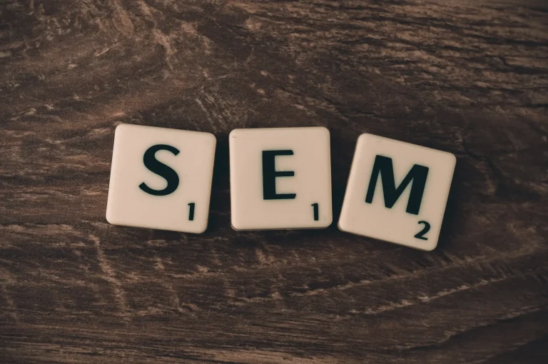 Três blocos de um jogo de palavras formam a sigla "SEM" (Search Engine Marketing) em letras pretas maiúsculas.