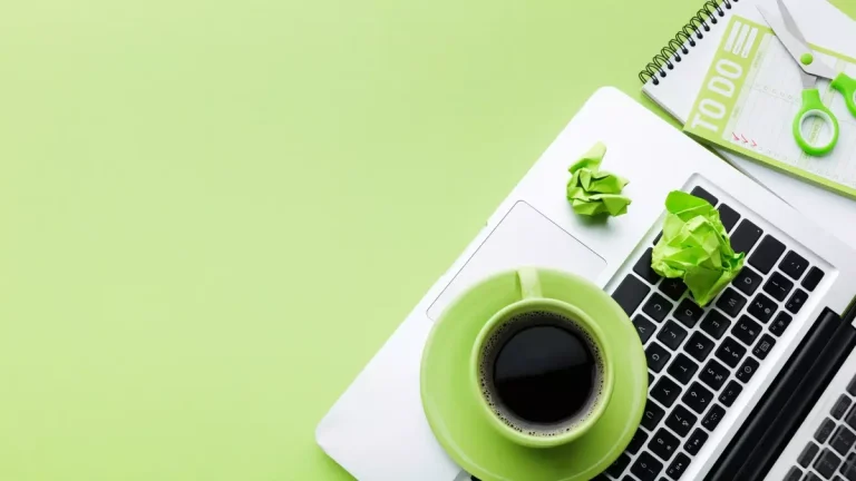 Imagem de um ambiente de trabalho com laptop, caderno, canetas, um copo de café e papéis amassados em notas de brainstorming, ressaltando a importância do marketing digital para empreendedores.