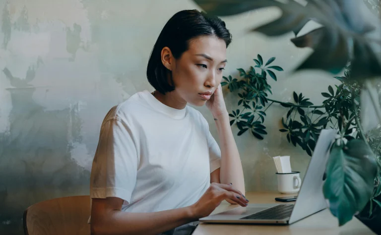 mulher asiatica trabalhando em um computador em como encontrar e consertar links quebrados no wordpress