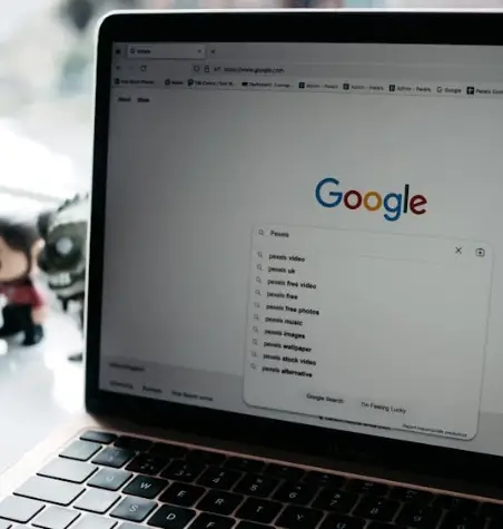 Tela de um notebook aberta no site do Google, com a barra de pesquisa exibindo sugestões automáticas de busca.