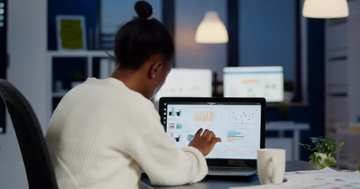 Pessoa analisando dados de marketing digital em um notebook, destacando a importância de investir em SEO para melhorar o posicionamento online. Ambiente de trabalho com tecnologia moderna.