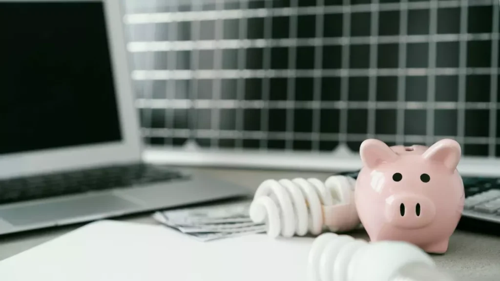Imagem com computador, lâmpada de energia e um cofrinho de porquinho rosa, representando estratégias para ganhar dinheiro com SEO.