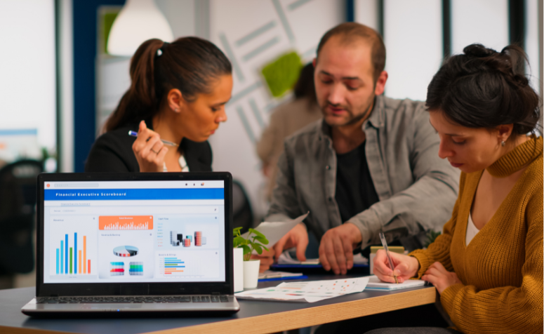 como-saber-se-sua-estrategia-de-conteudo-esta-funcionando Equipe de profissionais analisando resultados de uma estratégia de conteúdo em reunião de negócios, com gráfico de desempenho no laptop.