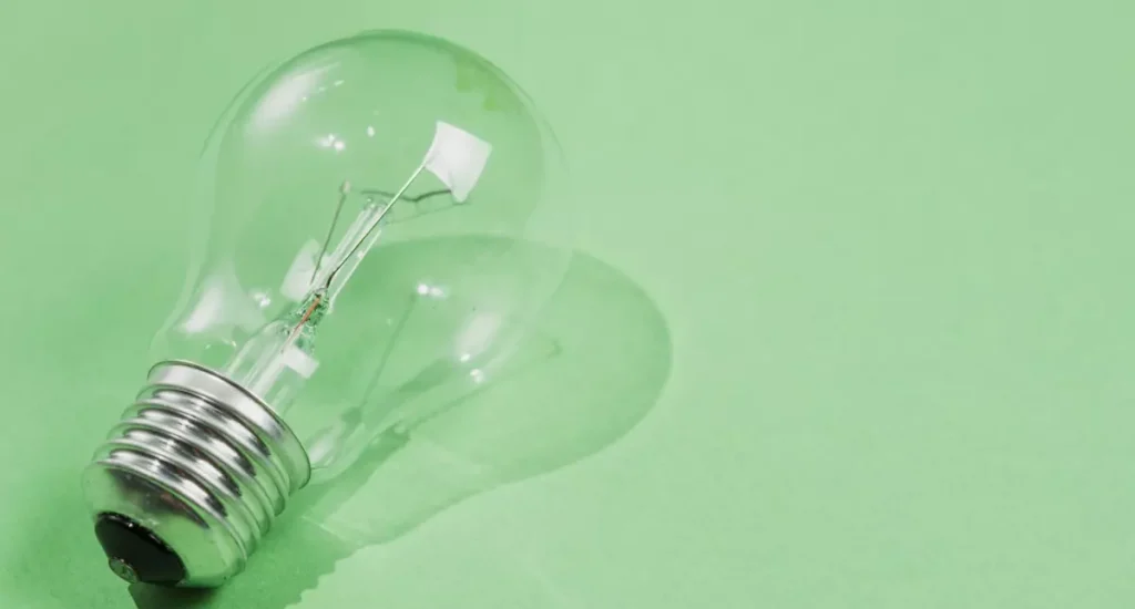 Ilustração de uma lâmpada transparente apagada sobre fundo verde, simbolizando ideias ou inovação de como usar schema markup sem código no WordPress