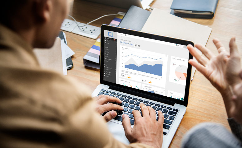 Pessoas analisando gráficos de métricas de SEO em uma reunião de escritório com laptop e documentos espalhados na mesa