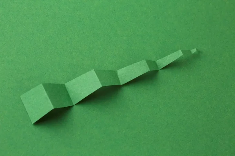 Imagem ilustrativa da estrutura ideal de heading tags para SEO, representada por uma linha de blocos de papel em diferentes tamanhos sobre fundo verde.