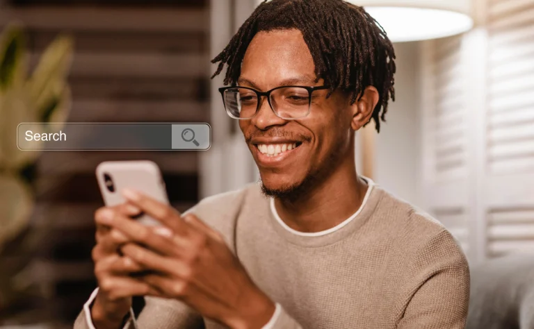 Homem sorridente usando smartphone com pesquisa do Google sobre impacto da IA no comportamento de busca dos usuários na tela.