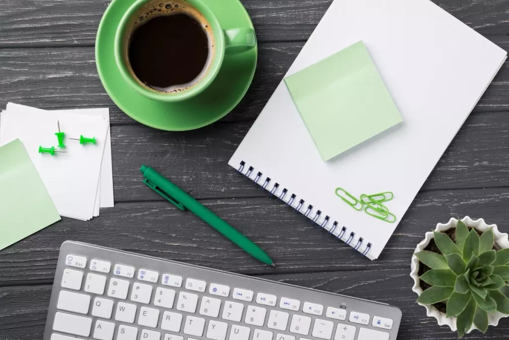 Imagem de um escritório com computador, caderno, post-its, clip de papel e uma planta, ideal para entender o que é um blog corporativo.